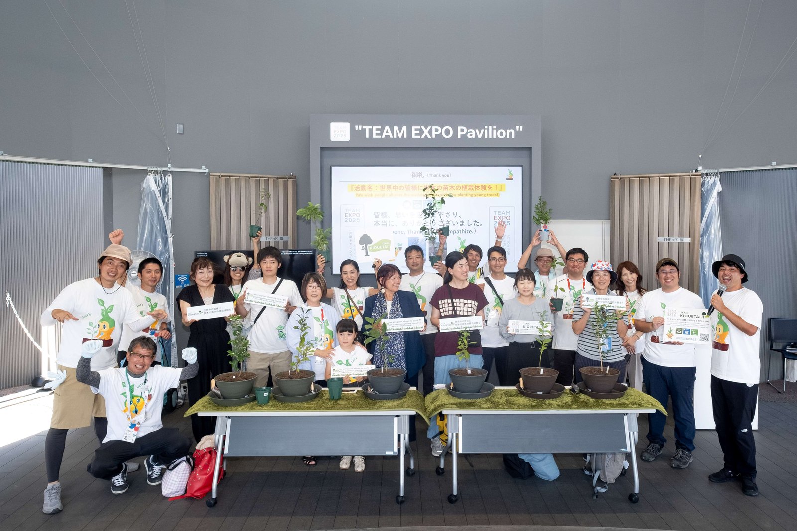 TEAM EXPOパビリオンで、植えた苗木と並ぶ参加者